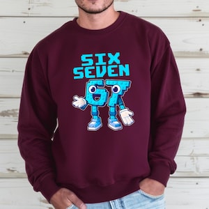 A man wearing a burgundy sweatshirt with a graphic design depicting a blue robot character and the text "SIX SEVEN" printed on it.