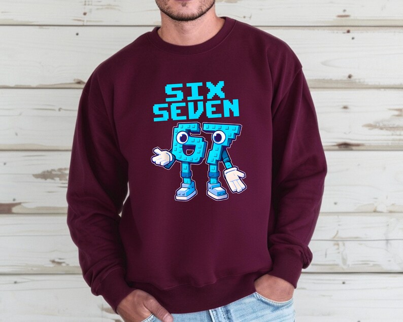 A man wearing a burgundy sweatshirt with a graphic design depicting a blue robot character and the text "SIX SEVEN" printed on it.