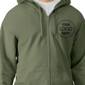 A man wearing a green zip-up hoodie with a logo on the front.