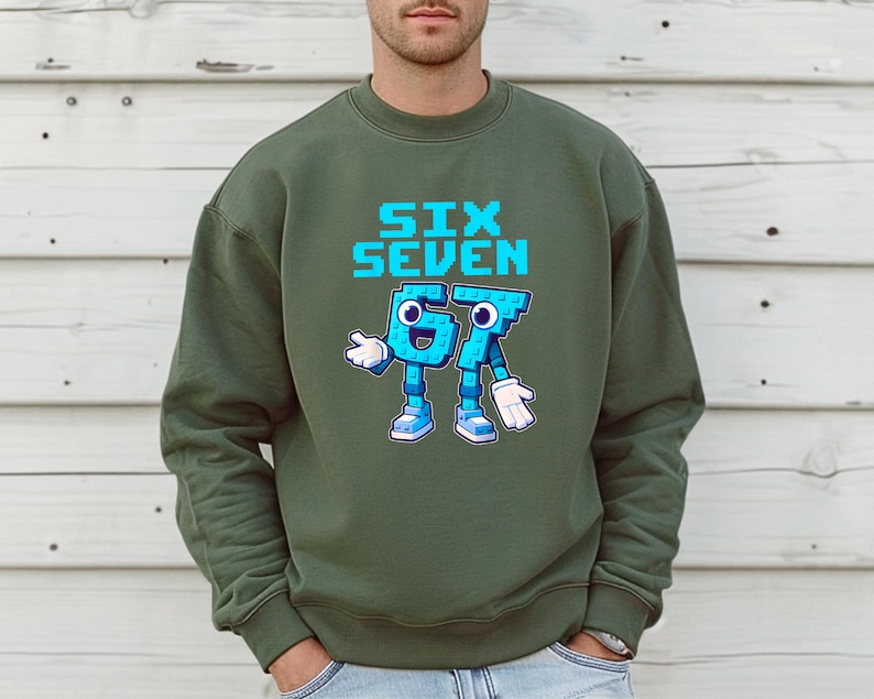 A man wearing a green sweatshirt with a graphic design of a blue robot character and the text "SIX SEVEN" printed on it.