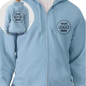 A man wearing a light blue hooded sweatshirt with a logo on the front.