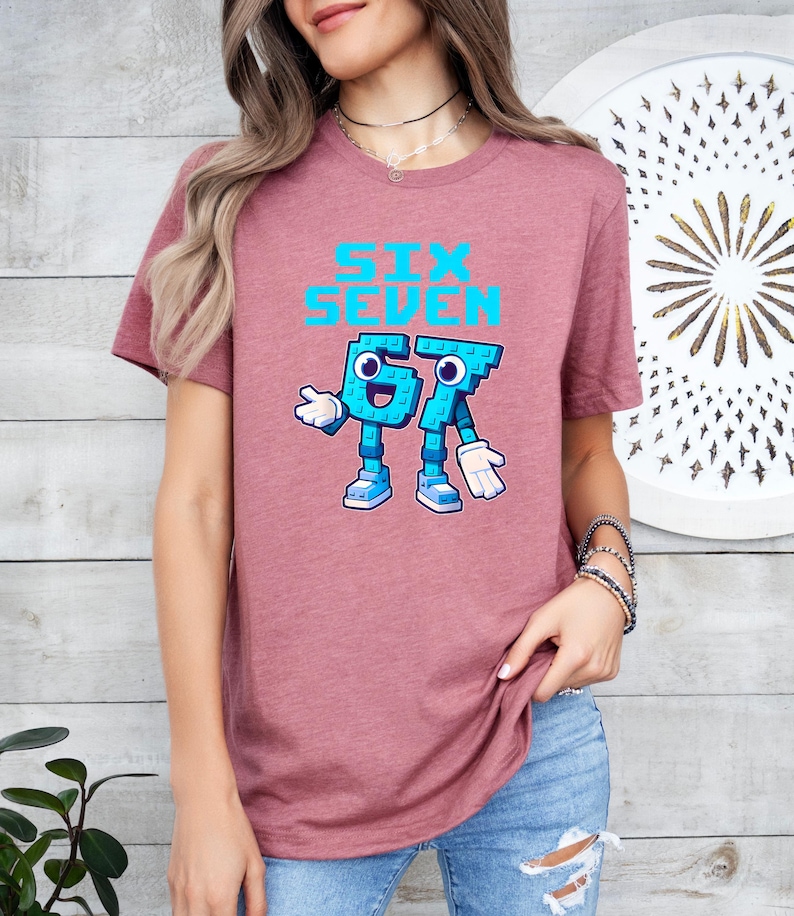 A woman wearing a pink t-shirt with a graphic design of a character and text printed on it.