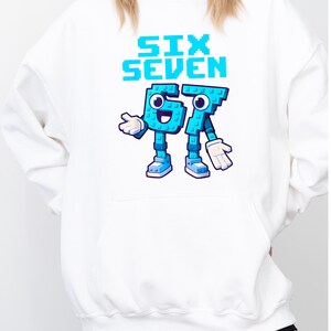 A white hoodie with a graphic design featuring a character that says "Six Seven" in blue and teal colors.