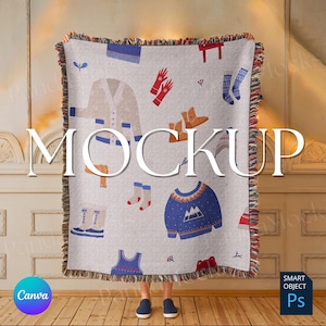 Puede incluir: Una manta de tejido blanco con un patrón colorido de ilustraciones de temática invernal, que incluyen guantes, botas, suéteres y sombreros. La manta tiene un borde de flecos y está drapeada sobre los hombros de una persona. El texto "MOCKUP" está superpuesto en la imagen.