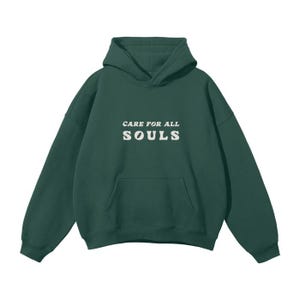 May include: A dark green hooded sweatshirt with the text "CARE FOR ALL SOULS" printed in white on the front.
