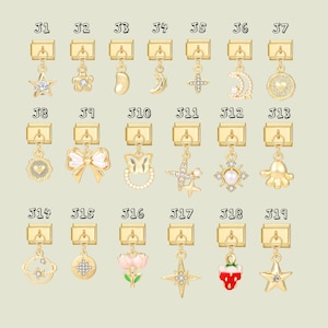 Può includere: Una collezione di ciondoli dorati con vari design, tra cui stelle, fiori, lune, fiocchi e un polpo. Ogni ciondolo è attaccato a una chiusura dorata, perfetto per bracciali o collane. I ciondoli sono esposti su uno sfondo beige chiaro.