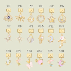 Puede incluir: Una colección de colgantes dorados con varios diseños celestiales y caprichosos. Los colgantes incluyen un ojo, un sol, una luna creciente, un corazón, una estrella y una mariposa. Cada colgante tiene un cierre.