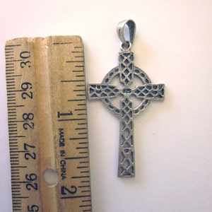 May include: A silver Celtic cross pendant with a detailed, intricate design. The pendant is approximately 1 inch in size and has a bail for attaching to a chain.