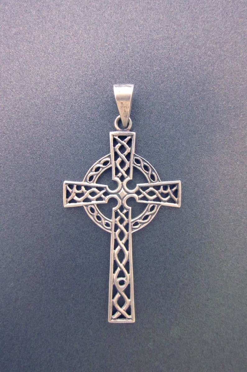 May include: A silver Celtic cross pendant with intricate knotwork design. The cross is detailed with a circle around the center.