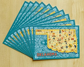 Puede incluir: Una pila de postales azules con un borde de patrón paisley. Las postales presentan un mapa de Oklahoma con el nombre del estado en una pancarta amarilla en la parte inferior. El mapa está lleno de pequeñas ilustraciones de puntos de referencia y ciudades de Oklahoma.