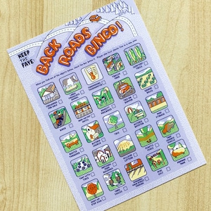 May include: A purple and blue bingo card with illustrations of various objects. The card is titled "Back Roads Bingo!" and has instructions to check the box below each object when found. The objects include a biker, a rusted thrasher, a tree, a tied-on bumper, a mini storage unit, a propane tank, a yard eagle, a stop sign, a mini golf course, a tarp covered vehicle, a plastic fence, a hillside letter, a matching farm building, a tire with tarps, a church, a novelty mailbox, a mom and pop motel, a fundraising thermometer, a large fiberglass animal, fireworks for sale, a trailer park, a cemetery tree, and a square bale.