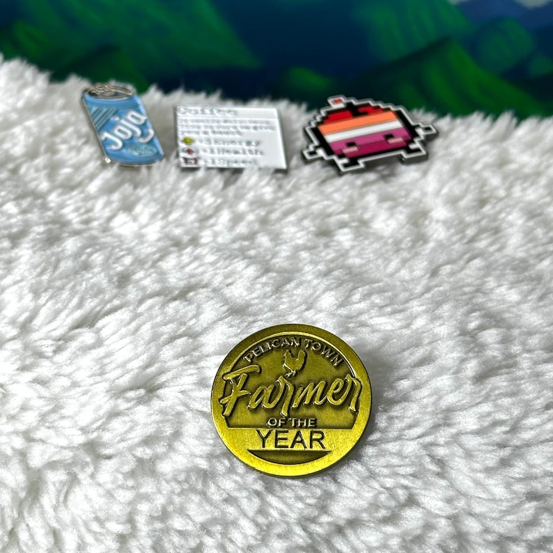 May include: Gold-colored pin with the text "Pelican Town Farmer of the Year" and a stylized chicken design.