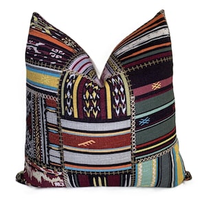 May include: A decorative pillow with a patchwork design. The pillow features a variety of colorful fabrics in shades of red, orange, yellow, green, and blue. The fabrics are stitched together with visible seams, creating a textured look. The pillow is square-shaped and has a soft, inviting appearance.