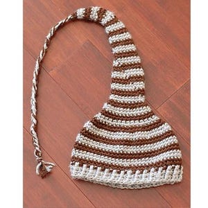 May include: A brown and white striped crocheted hat with a long tail. The hat is made with a soft yarn and has a comfortable fit.