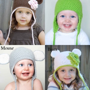 May include: Four children wearing crocheted hats with animal themes. The hats are brown, green, gray, and white with matching animal ears. The hats have long ties that hang down the back. The children are smiling and looking at the camera.