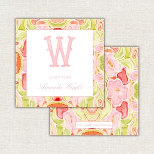 Op de afbeelding: Twee vierkante cadeaulabels met een aquarel bloemenontwerp in roze, groen en oranje. Het bovenste label heeft een wit midden met een roze "W" en de tekst "A GIFT FROM Amanda Wright". Het onderste label heeft de tekst "POLLARDPAPERDESIGNS".