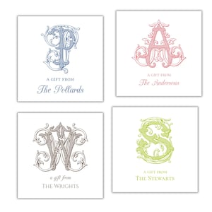 May include: Four square gift tags with decorative initial designs. Each tag features a different letter in a unique colour: blue, pink, grey, and green. The text "A Gift From" and a family name are printed below each initial.