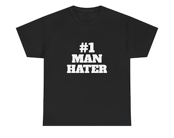 May include: Black t-shirt with the white text "#1 MAN HATER" in a bold, blocky font. The shirt has a crew neck and short sleeves. The text is centered on the chest.