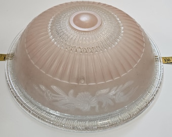 May include: A pink glass ceiling light fixture with a clear glass rim and a floral design. The light fixture has a dome shape and is approximately 10 inches in diameter.