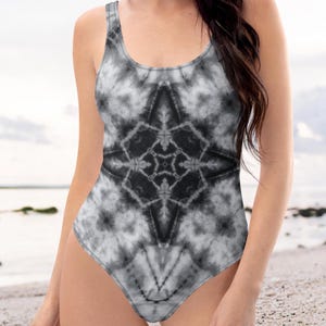 May include: A black and white tie-dye swimsuit with a geometric pattern. The swimsuit has a scoop neck and a low back.