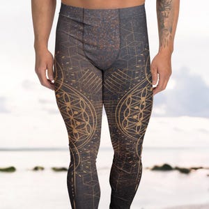 Puede incluir: Mallas negras con un patrón geométrico dorado. Las mallas presentan un diseño repetitivo de círculos y líneas interconectados, creando un patrón complejo. Las mallas se llevan con zapatillas blancas.