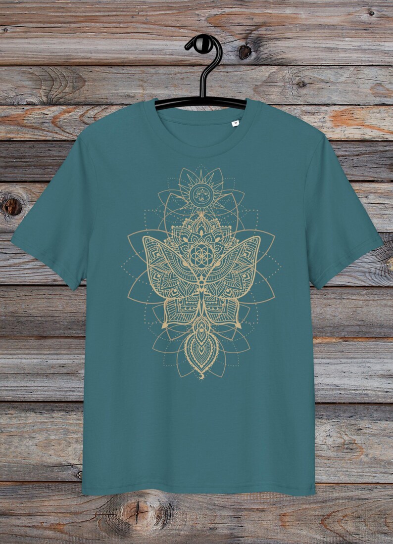 May include: A teal blue t-shirt with a gold mandala design featuring a butterfly and geometric patterns.