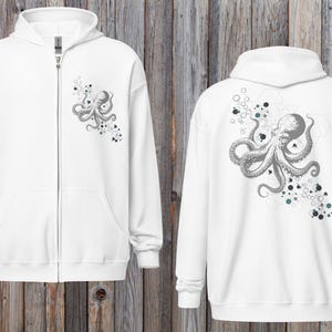 Peut inclure: Sweat à capuche blanc zippé avec un motif de poulpe gris détaillé à l'avant et à l'arrière. Le poulpe est entouré de formes géométriques et de petits points gris et turquoise. Le sweat à capuche a une capuche et une poche avant.