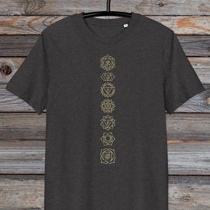 May include: A dark heather grey t-shirt with a vertical row of seven gold chakra symbols printed on the front. The symbols are in a line down the centre of the shirt.