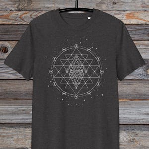 May include: A dark heather grey t-shirt featuring a white geometric design of a Sri Yantra, a sacred symbol in Hinduism, on the front.
