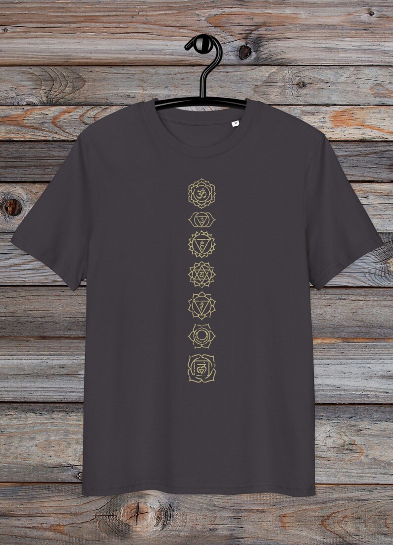 May include: A charcoal grey t-shirt with a vertical line of seven gold chakra symbols printed on the front. The symbols are in a line from top to bottom, starting with the crown chakra and ending with the root chakra.