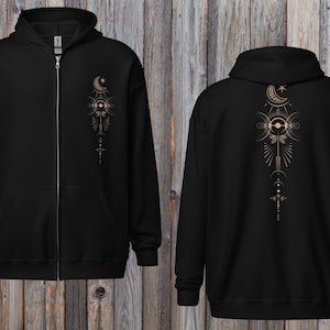 Peut inclure: Sweat à capuche noir zippé avec un motif céleste doré. L'avant présente un motif vertical avec des lunes, des étoiles et des formes géométriques. Le dos du sweat à capuche affiche un motif similaire, plus grand. Le sweat à capuche a une capuche et une fermeture éclair.