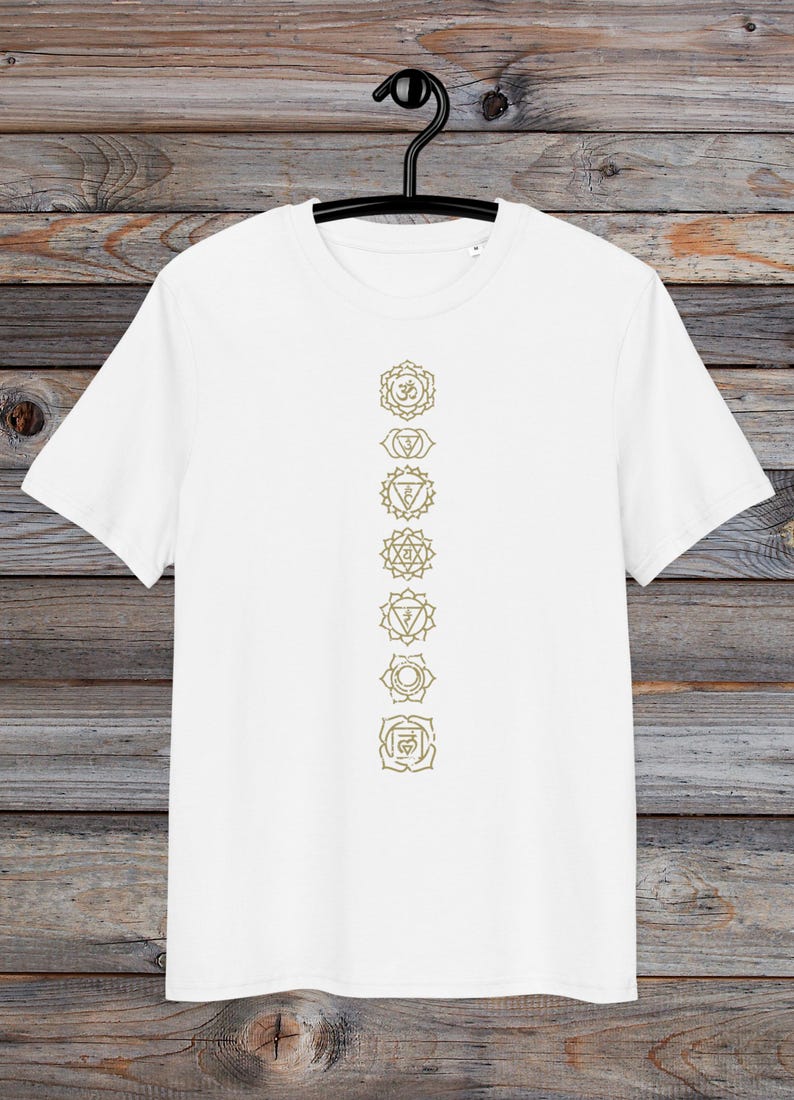 May include: White t-shirt with a vertical line of seven gold chakra symbols printed on the front.