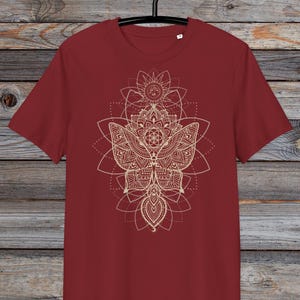 May include: A maroon t-shirt with a gold mandala design featuring a butterfly and geometric patterns.