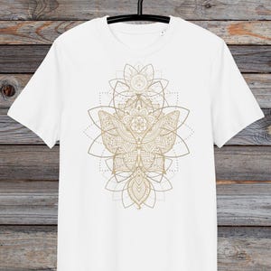 May include: White t-shirt with a gold mandala design featuring a butterfly and geometric patterns.