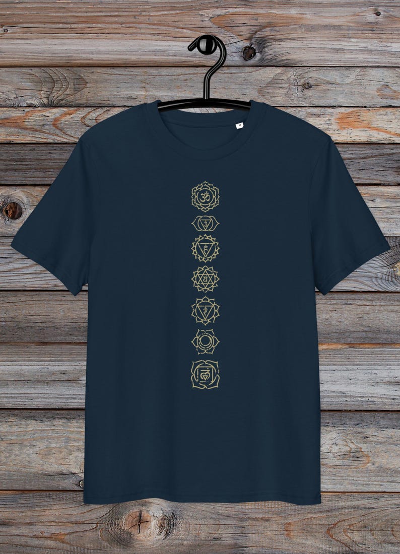 May include: A navy blue t-shirt with a vertical row of seven gold chakra symbols printed on the front. The symbols are in a line down the centre of the shirt.
