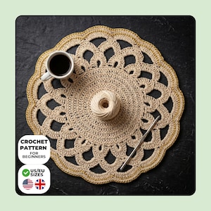 May include: A beige crochet doily with a gold border, a ball of yarn, and a crochet hook. A cup of coffee sits on the doily. Text on the image reads "CROCHET PATTERN FOR BEGINNERS" and "US/EU SIZES".