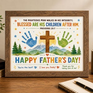 May include: A framed Father's Day print in a brown wooden frame. The print includes a cross, handprints, mountains, and the text "Happy Father's Day!" and a Bible verse. The print is decorated with stars and hearts.