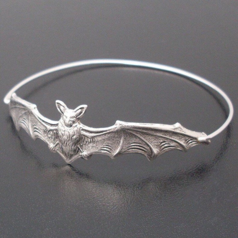 Pu&ograve; includere: Un braccialetto rigido in argento con un designo di pipistrello dettagliato. Il pipistrello &egrave; centrato sul braccialetto e ha le ali che si estendono fino ai bordi del braccialetto.