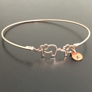 Puede incluir: Un brazalete de oro rosa con dos dijes de elefante y un peque&ntilde;o dije con la letra K.