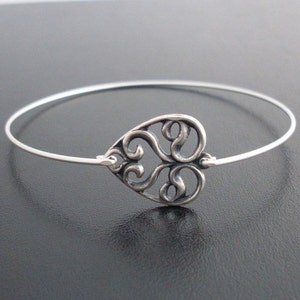 Puede incluir: Un brazalete de plata con un delicado encanto de coraz&oacute;n calado. El encanto de coraz&oacute;n est&aacute; hecho de plata y tiene un dise&ntilde;o de filigrana.