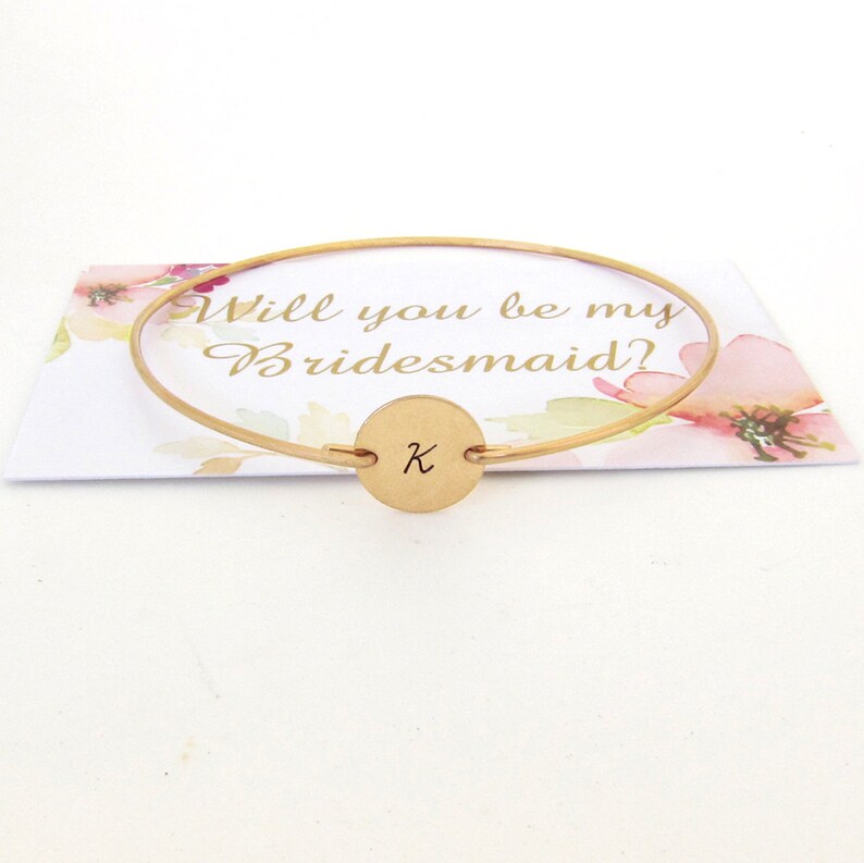 Puede incluir: Pulsera de oro para propuesta de dama de honor con un dije redondo grabado con la letra "K" y una tarjeta que dice "&iquest;Quieres ser mi dama de honor?"