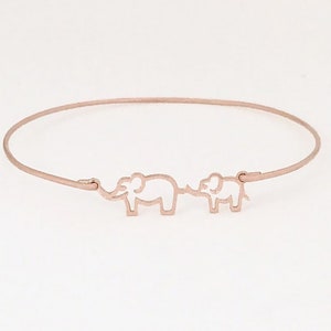 Puede incluir: Un brazalete de oro rosa con dos siluetas de elefantes. Los elefantes se miran y est&aacute;n conectados por una l&iacute;nea fina.