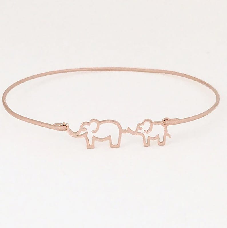 Puede incluir: Un brazalete de oro rosa con dos siluetas de elefantes. Los elefantes se miran y est&aacute;n conectados por una l&iacute;nea fina.