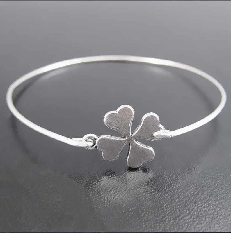 May include: A silver bracelet with a four-leaf clover charm.
