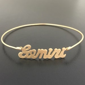 Pode incluir: Um bracelete dourado com o nome "Samira" escrito em letra cursiva.