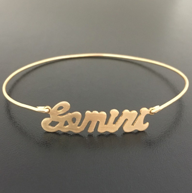 Pode incluir: Um bracelete dourado com o nome "Samira" escrito em letra cursiva.