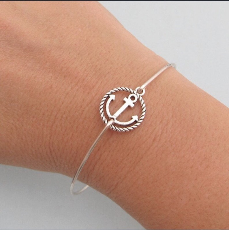 K&ouml;nnte beinhalten: Ein silbernes Armkettchen mit einem seil&auml;hnlichen Design und einem Anker-Anh&auml;nger.