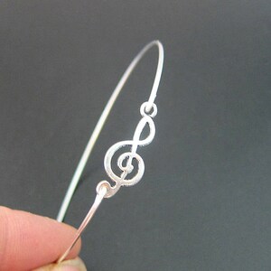 May include: A silver bracelet with a treble clef design.