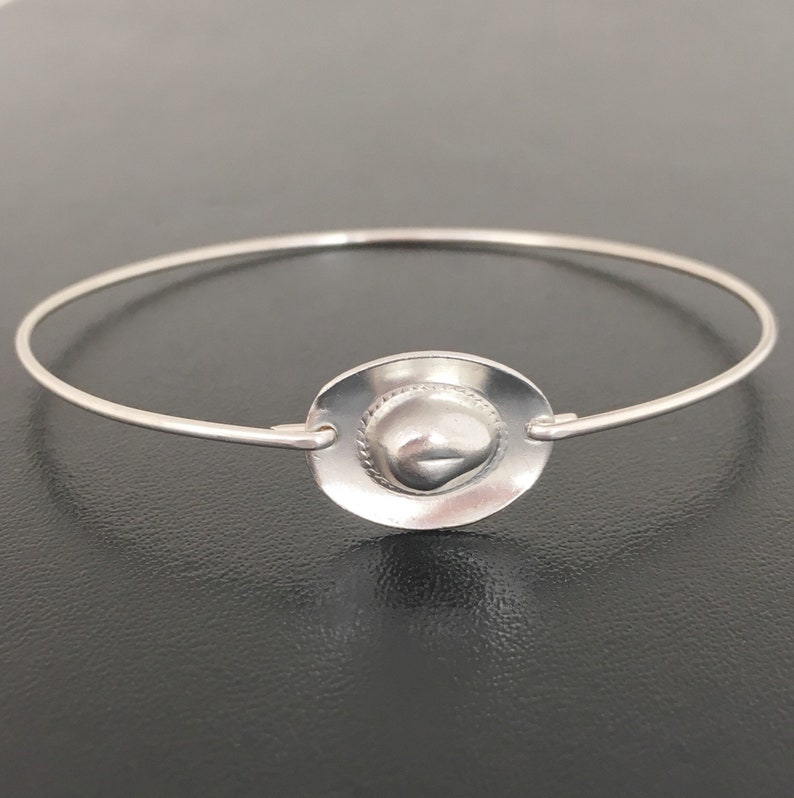 May include: A silver bracelet with a charm in the shape of a cowboy hat.