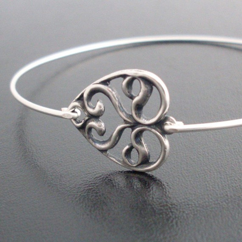 Puede incluir: Un brazalete de plata con un delicado encanto de coraz&oacute;n calado. El encanto de coraz&oacute;n est&aacute; hecho de plata y tiene un dise&ntilde;o de filigrana.